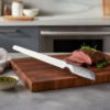 Cuchillo CRC de acero cortando sobre una tabla en una cocina.