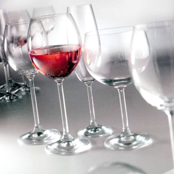 Copas cristal, una con vino sobre fondo blanco