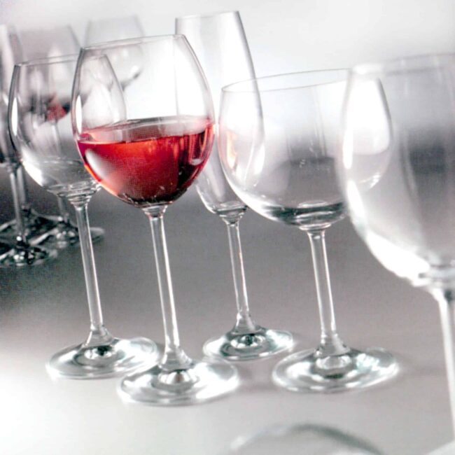 Copas cristal, una con vino sobre fondo blanco