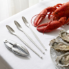 Set de utensilios para marisco con langosta y rodajas de limón sobre una mesa
