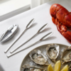 Set de utensilios para marisco con langosta y rodajas de limón sobre una mesa