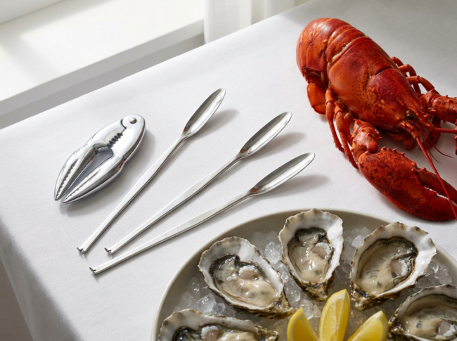 Set de utensilios para marisco con langosta y rodajas de limón sobre una mesa