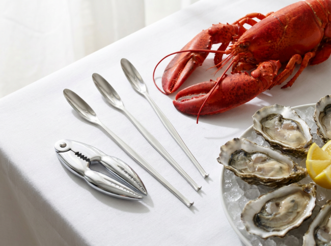 Set de utensilios para marisco con langosta y rodajas de limón sobre una mesa