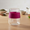 Vasos de doble pared de borosilicato sobre una mesa de madera con una tetera al fondo.