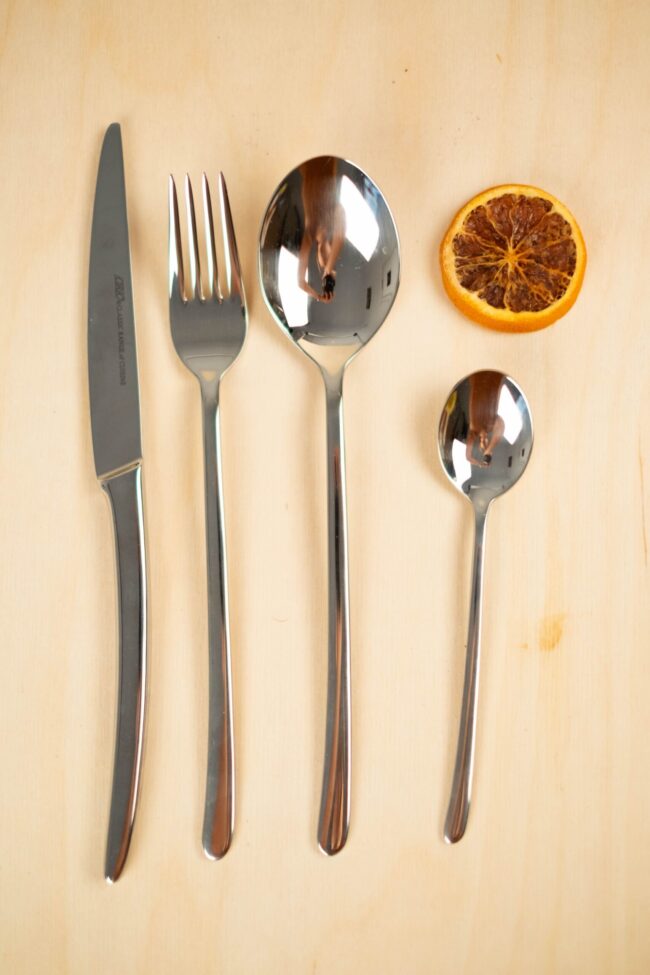 Imagen de cuberteria sobre fondo marron claro, chuchillo, tenedor, cucharagrande y pequeña. Pertenece al juego de cuberteria trento de 24 piezas de acero inoxidable.