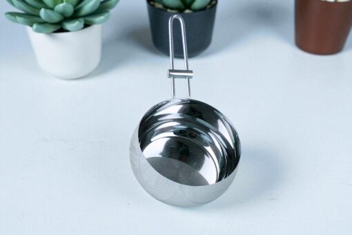 cazo de acero inoxidable de napoles de 16cm, sobre una mesa blanca y plantas de decoracion el la parte superior